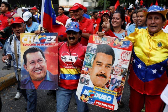 Manifestantes pró-governo seguram cartazes com as fotos de Hugo Chávez e Nicolás Maduro