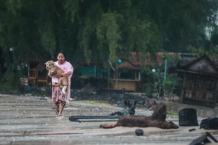 Mulher corre para casa enquanto a tempestade tropical Pabuk se aproxima. (Krittapas Chaipimon/Reuters)