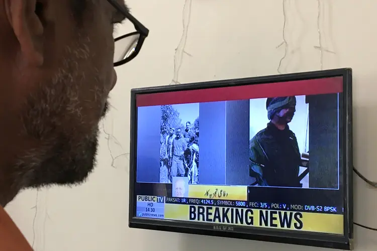 Karachi, Paquistão: um homem olha para uma tela de televisão exibindo a foto do piloto indiano que teria sido capturado pelo Paquistão em 27 de fevereiro de 2019 (Akhtar Soomro/Reuters)