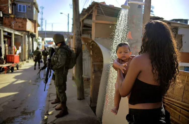 Maguinhos: militares junto a uma mulher com seu filho em uma rua da favela de Manguinhos, em 18 de fevereiro de 2018 (Eugenia Logiuratto/AFP)