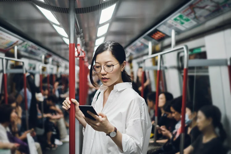 Young businesswoman looking at smartphone while riding on subway (Getty Images/Divulgação)