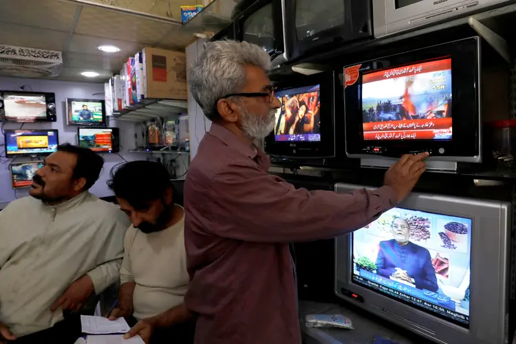 PAQUISTÃO: televisores mostram imagens de dois caças indianos abatidos por forças militares paquistanesas / REUTERS/Akhtar Soomro