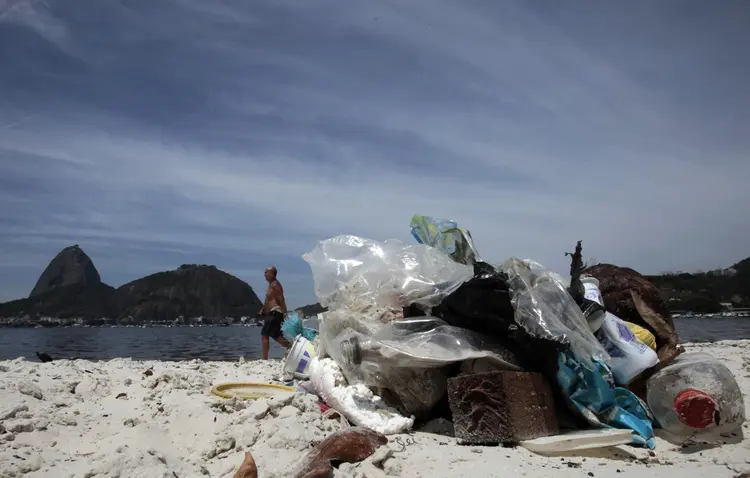 Rio de Janeiro: homem caminha em meio ao lixo na praia de Botafogo, com o Pão de Açúcar ao fundo (Sergio Moraes/Reuters)