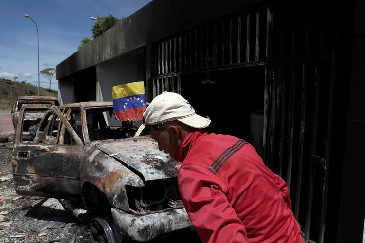Caos na fronteira: homem caminha entre carros queimados na fronteira do Brasil com a Venezuela (Ricardo Moraes/Reuters)