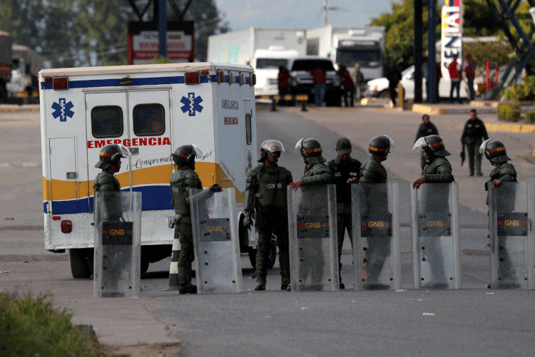 Ambulância passa por policiais na Venezuela (Ricardo Moraes/Reuters)