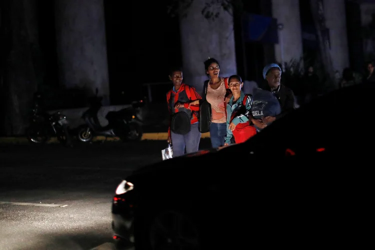 Pessoas atravessam rua durante blecaute em Caracas
 (Carlos Jasso/Reuters)