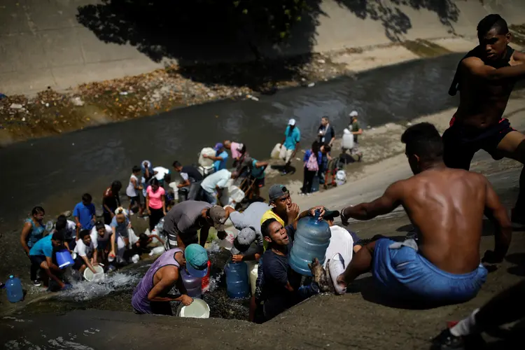 Venezuelanos buscam água em dreno de esgoto (Carlos Garcia Rawlins/Reuters)