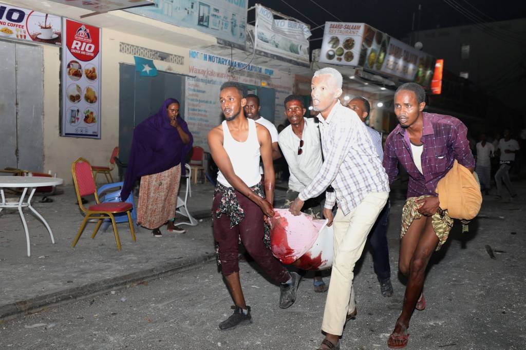 Somália: pessoas carregam vítima de atentado terrorista com caminhão-bomba que explodiu contra um hotel de Mogadishu em Maka Al Mukaram, Mogadíscio (Feisal Omar/Reuters)