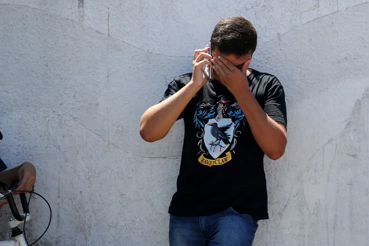 Homem fala ao telefone em frente à escola alvo de tiroteio em Suzano (SP) (Amanda Perobelli/Reuters)