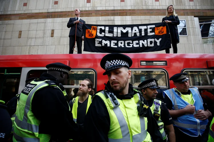 Policiais e manifestantes contra as mudanças climáticas durante protesto em estação de trem em Londres.  (Henry Nicholls/Reuters)
