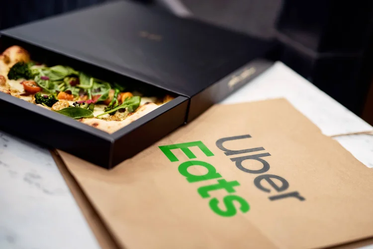 Caixa de pizza aberta e embalagem com o logo do Uber Eats (Uber Eats/Divulgação)