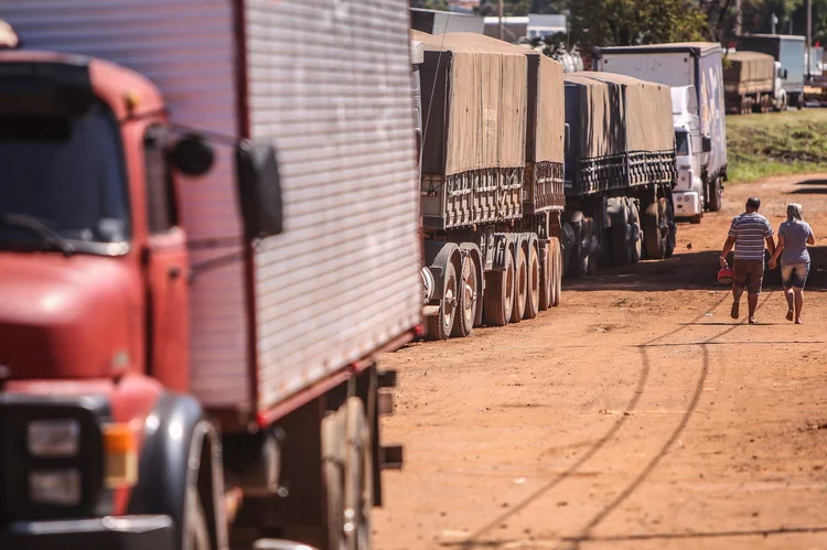 Pessoas andam ao lado de caminhões na BR 040 , em Goiás (Andre Coelho/Bloomberg)