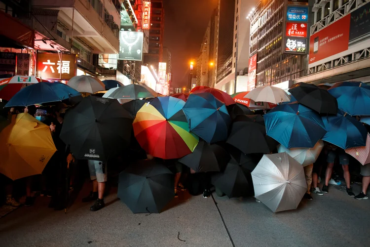 Manifestantes seguram guarda-chuvas para se proteger da polícia em Hong Kong: manifestantes jogaram guarda-chuvas e capacetes contra a polícia, que revidou balançando cassetetes e disparando spray de pimenta (Thomas Peter/Reuters)