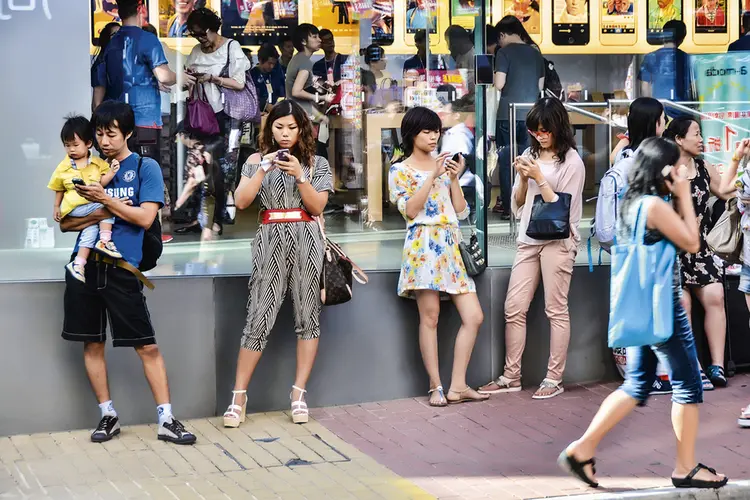 Pessoas com o smartphone em Hong Kong: o uso compulsivo de tecnologia virou um problema para consumidores e fabricantes (Alamy/Fotoarena/Reprodução)