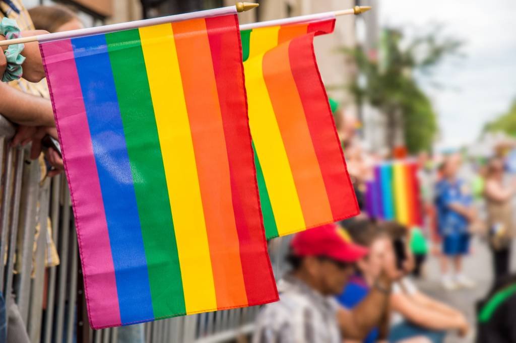 Gay rainbow flags at Montreal gay pride parade with blurred spectators in the background (MarcBruxelle/Getty Images)