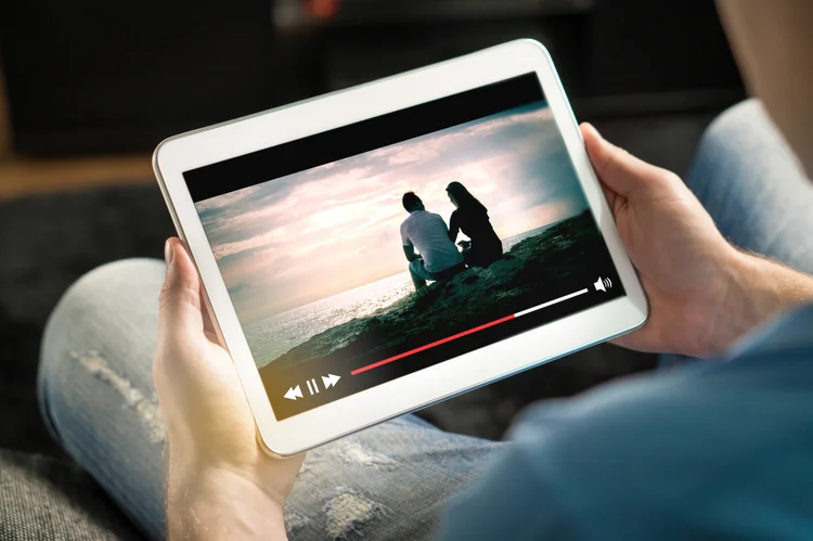 Online movie stream with mobile device. Man watching film on tablet with imaginary video player service. (Tero Vesalainen/Getty Images)