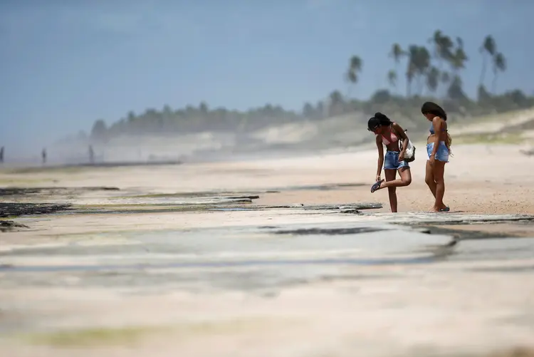 Óleo na praia: turistas são vistos próximos a uma mancha e óleo na praia o Sitio do Conde na cidade de Conde, na Bahia (Adriano Machado/Reuters)