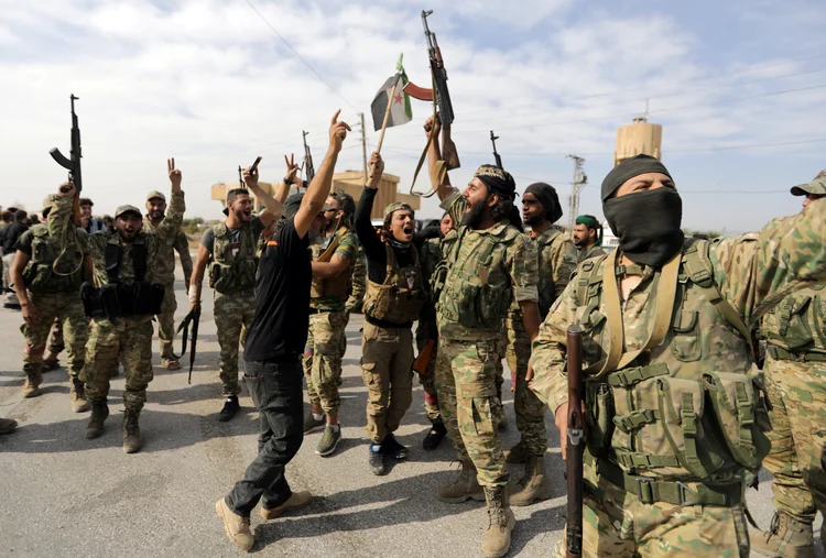 Turkey-backed Syrian rebel fighters react as they hold their weapons at the border town of Tel Abyad, Syria, October 14, 2019. REUTERS/Khalil Ashawi (Khalil Ashawi/Reuters)