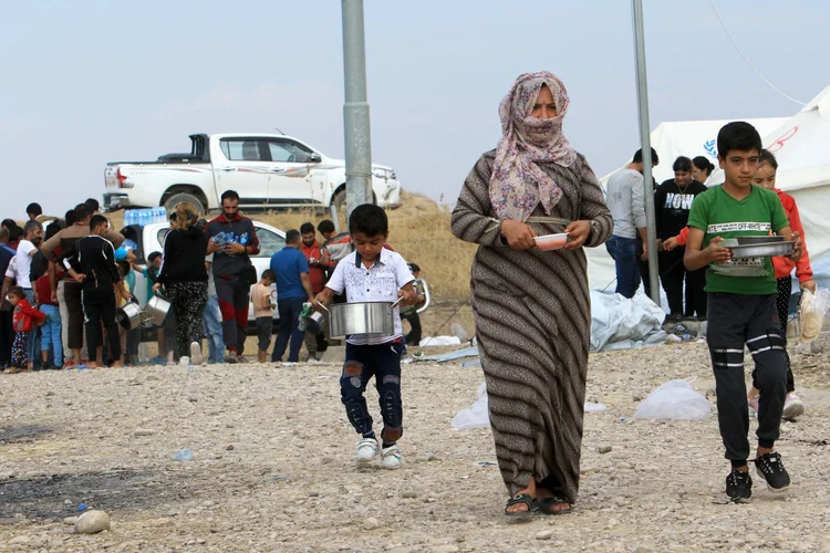 Syrian displaced families, who fled violence after the Turkish offensive in Syria, get food from Barzani charity at a refugee camp in Bardarash on the outskirts of Dohuk, Iraq October 18, 2019. REUTERS/Ari Jalal (Ari Jalal/Reuters)