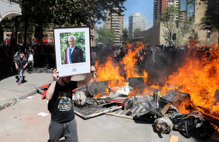 Santiago: manifestante gesticula com uma foto do presidente Sebastian Piñeira, do Chile (Ivan Alvarado/Reuters)