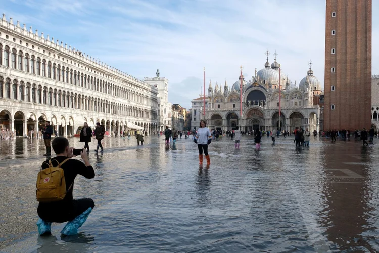 Turistas tiram fotos na Praça de São Marco inundada em Veneza, dia 16/11/2019 (Manuel Silvestri/Reuters)