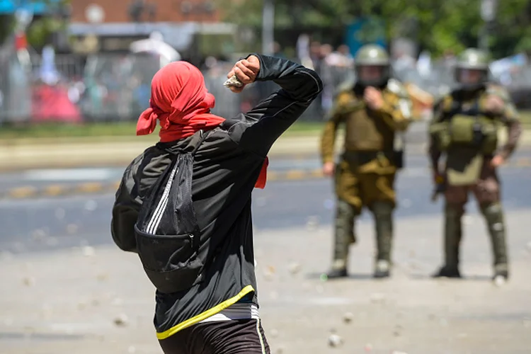 Chile: manifestante arremessa pedra em protestos de terça-feira (12) em Santiago (Claudio Santana/Getty Images)