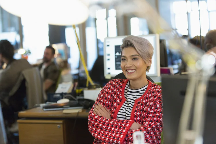 Mulher sorrindo no trabalho (Caiaimage/Chris Ryan/Getty Images)