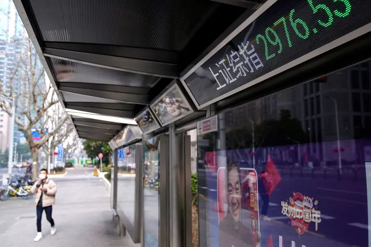 Xangai: homem usando máscara passa por uma placa eletrônica mostrando os índices de ações de Xangai e Shenzhen (Aly Song/Reuters)