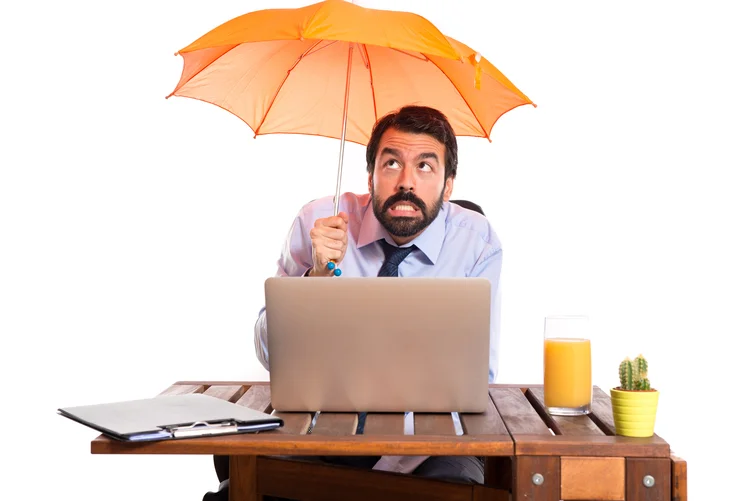 Businessman in his office holding an umbrella (Designed by luis_molinero / Freepik/Creative Commons)