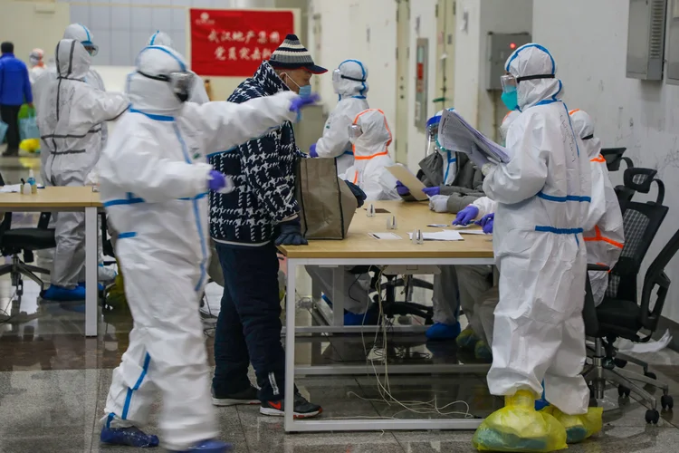 Médicos: vestidos com trajes especiais, profissionais atendem paciente em hospital provisório montado em Wuhan, na província de Hubei, para tratamento de coronavírus (China Daily via/Reuters)