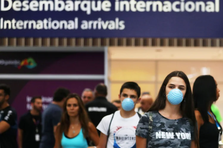 Aeroporto: pessoas desembarcam no Brasil com máscaras de proteção (Pilar Olivares/Reuters)