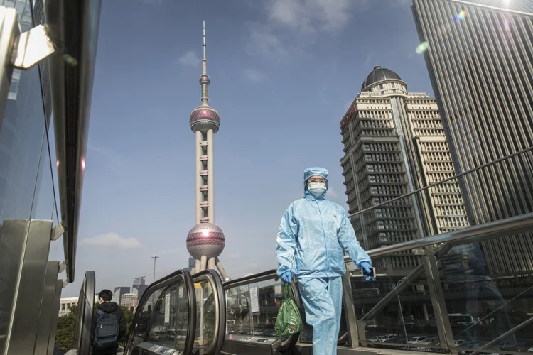 Pessoa com máscara e roupa protetora caminha em Xangai, na China 27/02/2020 (Qilai Shen/Bloomberg)