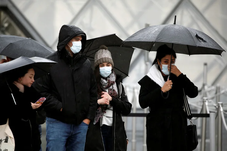 Turistas de máscaras próximos ao Louvre: França fechou diversos locais para evitar propagação (Benoit Tessier/Reuters)