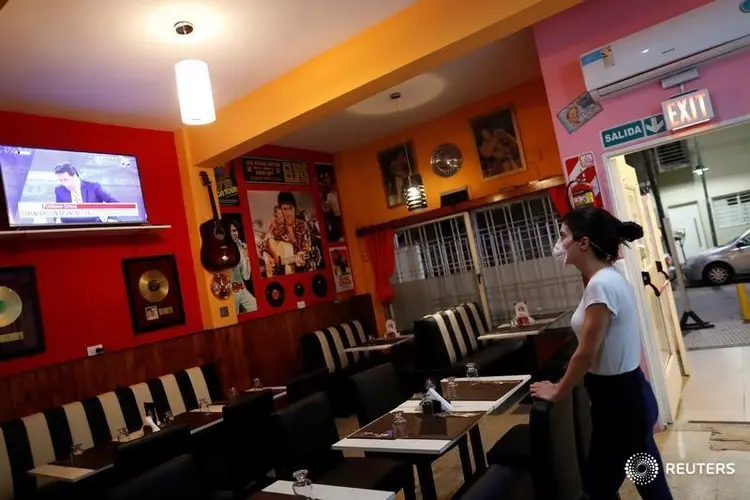 Garçonete assiste TV em restaurante vazio em Buenos Aires: crise com coronavírus (Agustin Marcarian/Reuters)