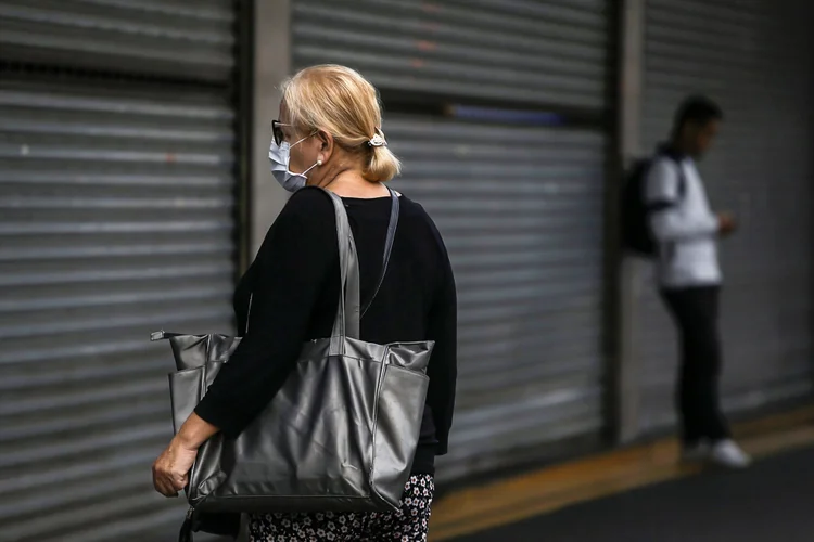 Mulher em frente à loja: efeitos da pandemia aparecerão nos dados de março, mas são "imprevisíveis" (Rahel Patrasso/Reuters)