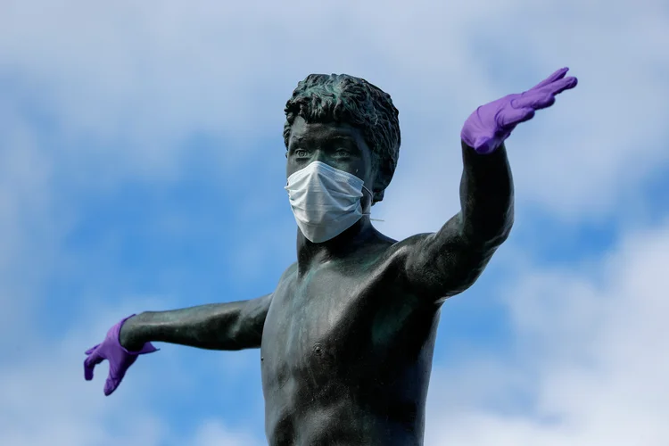 Estátua de surfista decorada com máscara e luvas em meio ao surto da doença do coranvírus (Covid-19), em Encinitas, Califórnia, EUA
 (Mike Blake/Reuters)