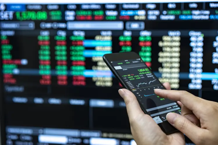 Businessman checking stock market data. He using a mobile phone. Analysis economy data on forex earn graph. (Witthaya Prasongsin/Getty Images)