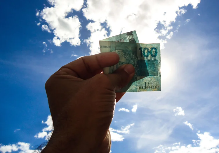 Nota de 100 reais é vista com o céu de fundo  (Felipe Queiroz Alves / EyeEm/Getty Images)