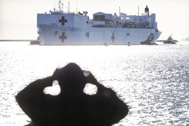 Homem observa chegada de um navio-hospital ao porto de Los Angeles, para ajudar com a pandemia de coronavírus. 27 de março de 2020, Califórnia, EUA (Mario Tama/Getty Images)