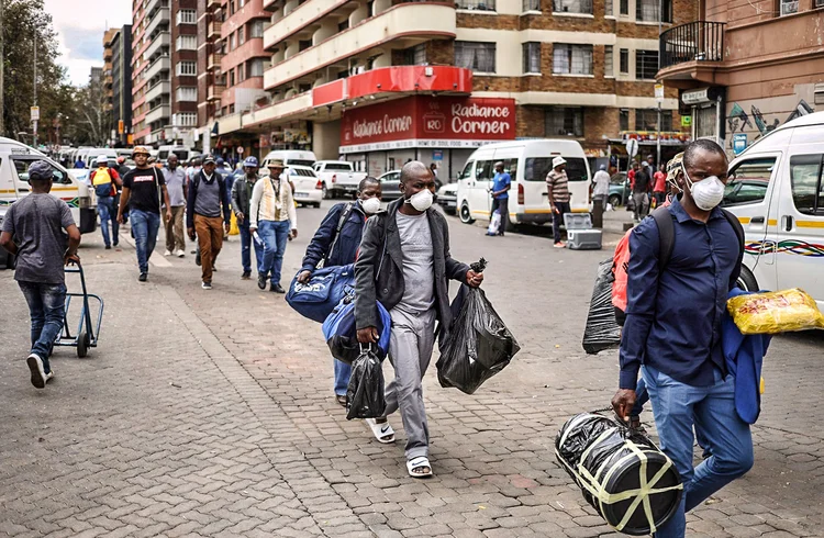 Passengers wearing masks walk to a taxi rank as residents of a number of African cities where the coronavirus is spreading are heading to the countryside to try to escape from the disease, in Johannesburg, South Africa, March 25, 2020. REUTERS/Siphiwe Sibeko (Siphiwe Sibeko/Reuters)