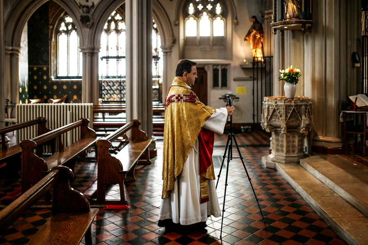 Padre arrumar celular para realizar missa de Páscoa por videoconferência, em Londres (Henry Nicholls/Reuters)