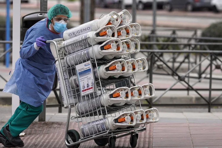 Trabalhador da saúde leva tanques de oxigênio à emergência de hospital de Madri, espanha: 30 de março de 2020.  (Paul Hanna/Bloomberg)