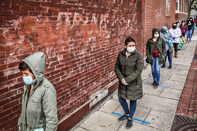 Pessoas esperam em fila de distribuição de alimentos doados por empresas locais a famílias carentes no Chelsea, bairro de Nova York (EUA), em 14 de abril de 2020 (Erin Clark para o Boston Globe/Getty Images)