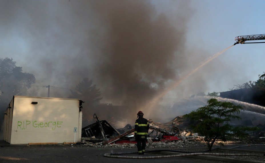 A fire fighter works to put out a burning business as the sun rises after another night of continued demonstrations after African-American man George Floyd was killed while in police custody days ago in Minneapolis, Minnesota, U.S., May 30, 2020. REUTERS/Leah Millis