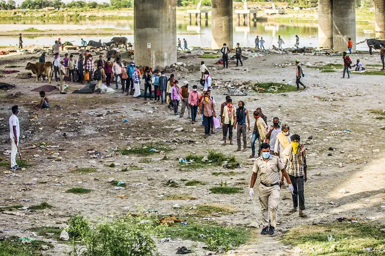 Pessoas à margem do rio Yamuna para serem transferidas para um abrigo durante um bloqueio imposto devido ao coronavírus em Nova Délhi, em 15 de abril. (Prashanth Vishwanathan/Bloomberg)