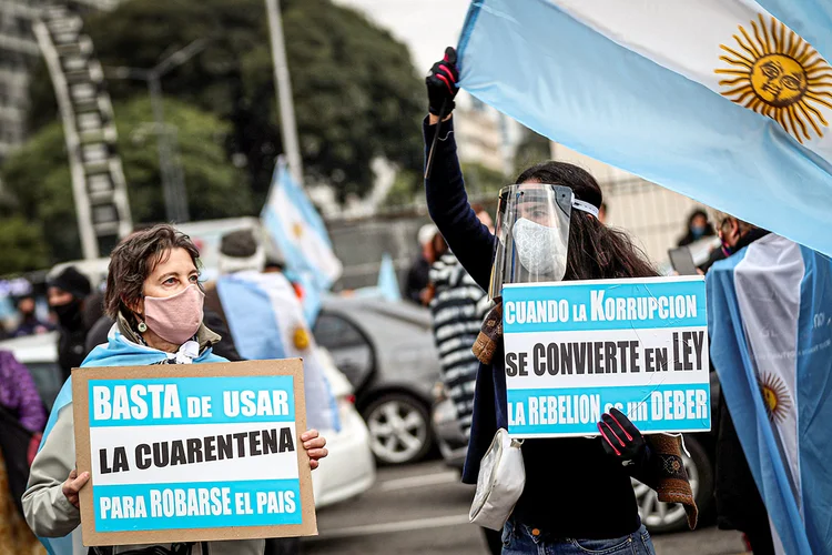 Manifestantes seguram cartazes com os dizeres: "parem de usar a quarentena para roubar o país", durante ato contra a estatização da exportadora argentina Vicentín e contra as medidas de quarentena em função da covid019. Buenos Aires, Argentina, em 20 de junho de 2020.  (Agustin Marcarian/Reuters)