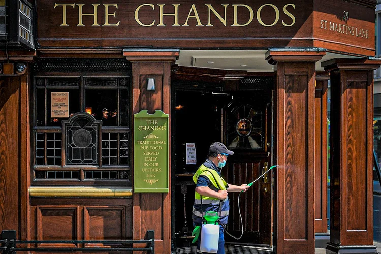Homem joga desinfetante no exterior de pub em Londres: (Toby Melville/Reuters)
