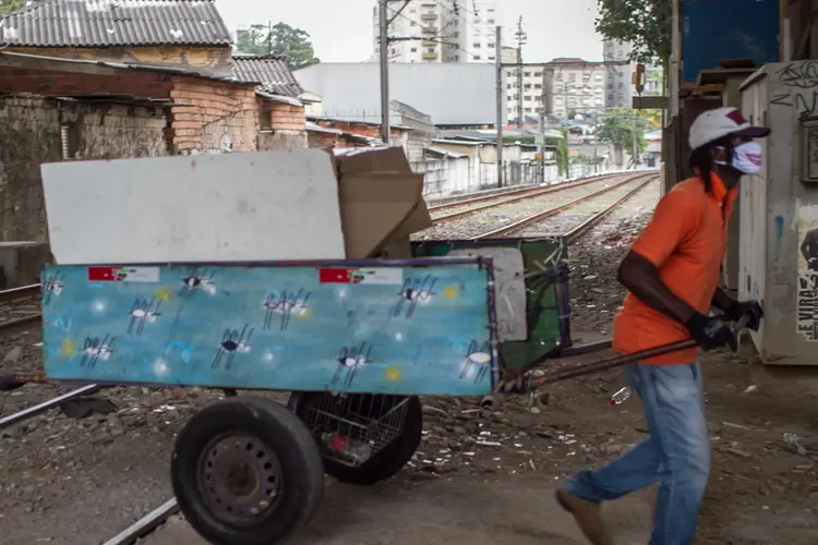 Homem usando máscara protetora puxa carrinho pelos trilhos de trem na Favela do Moinho, em São Paulo, Brasil, na quinta-feira, 25 de junho de 2020. (Marcelo Rochas/Bloomberg)