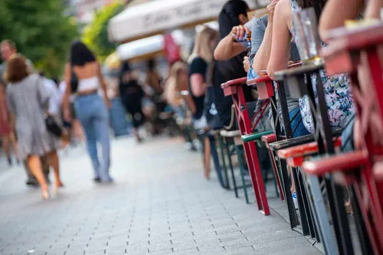 Pessoas andam na calçada ao lado de mesas de restaurante cheias de clientes na cidade de Hamburgo, Alemanha. 26 de junho de 2020.  (Jonas Walzberg/Getty Images)