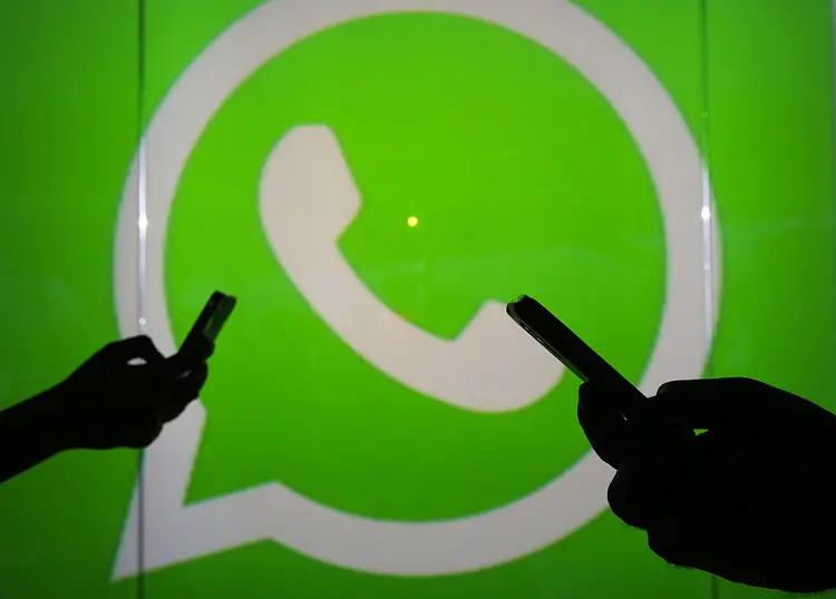 People are seen as silhouettes as they check mobile devices whilst standing against an illuminated wall bearing WhatsApp Inc's logo in this arranged photograph in London, U.K., on Tuesday, Jan. 5, 2016. WhatsApp Inc. offers a cross-platform mobile messaging application that allows users to exchange messages. Photographer: Chris Ratcliffe/Bloomberg via Getty Images (Bloomberg/Getty Images)